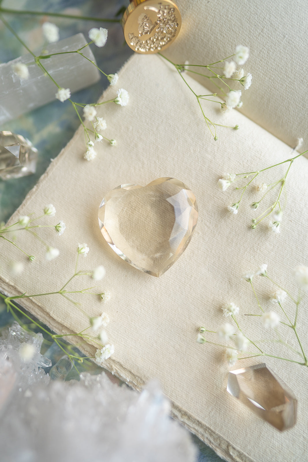 Faceted Citrine heart amongst a journal surrounded by flowers, wax seal, selenite, quartz and citrine towers in a romantic monet style sight